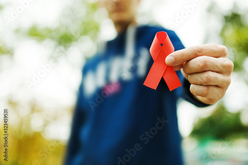 red aids ribbon in hand on green background, HIV