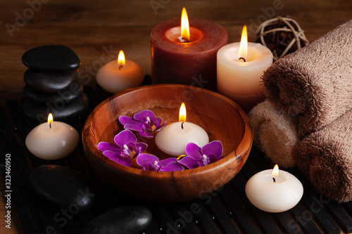 Aromatherapy, spa, beauty treatment and wellness background with massage stone, orchid flowers, towels and burning candles...