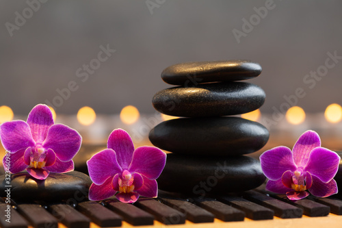 Massage stone  orchid flowers and burning candles. Spa and beauty background.