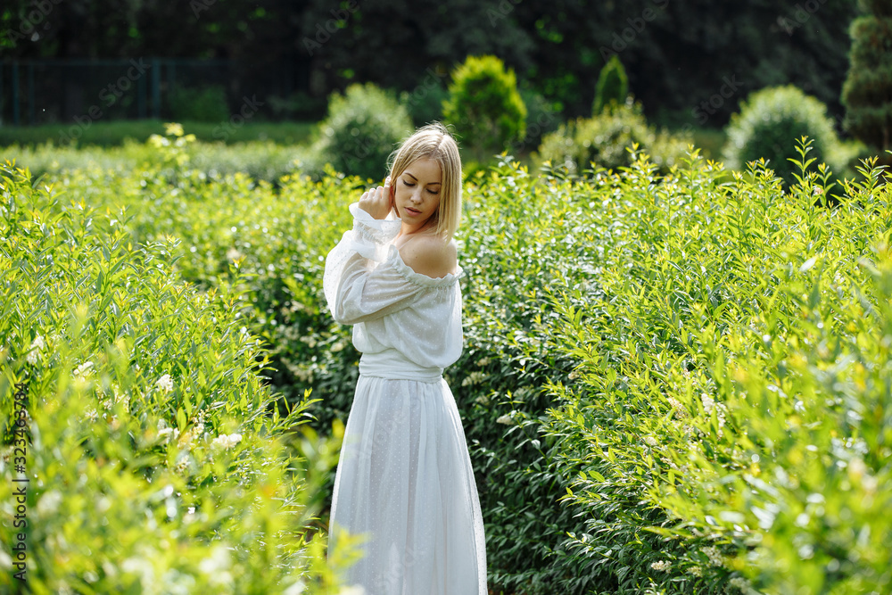 Fototapeta premium blonde in a white dress and a beautiful smile in the backlight