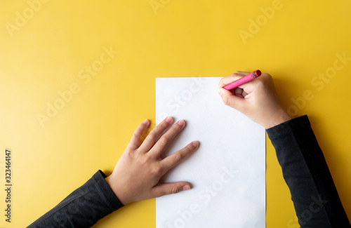 a child draws on the yellow table. Top view