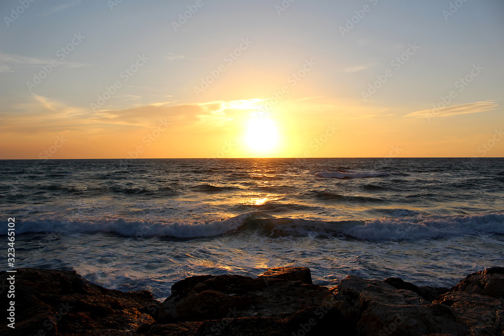 sunset at the rocky beach of Tel Aviv with unsettled waves