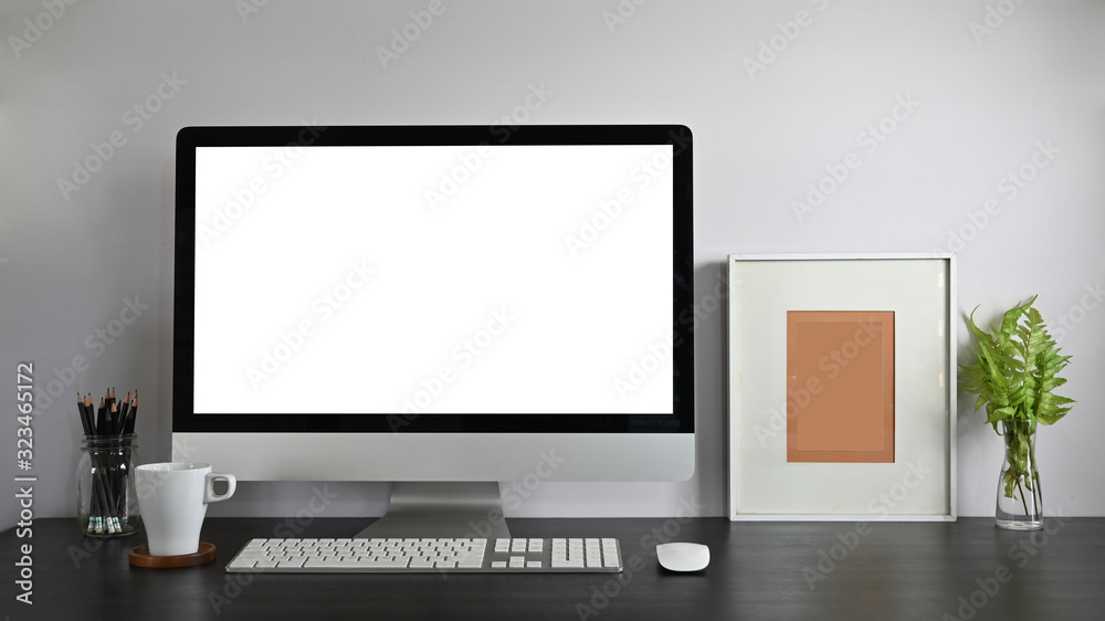 Personal workspace computer with blank screen, pencil holder, picture frame, potted plant, and coffee cup putting together on modern wooden table with white wall as background. Personal workspace computer with blank screen, pencil holder, picture frame, potted plant, and coffee cup putting together on modern wooden table with white wall as background.