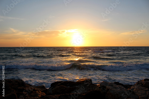 sunset at the rocky beach of Tel Aviv with unsettled waves © Jasmin