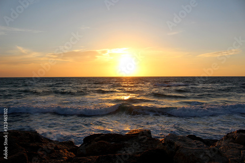 sunset at the rocky beach of Tel Aviv with unsettled waves