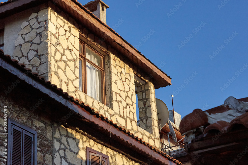 Fragment of an old stone house with wooden shutters and windows