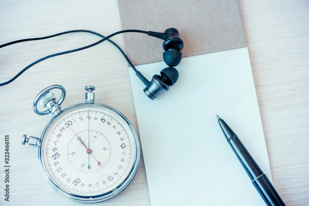 Notepad, pen, headphone And Stopwatch biege desk table background. The concept of home schooling, education, training Notepad, pen, headphone And Stopwatch biege desk table background. The concept of home schooling, education, training