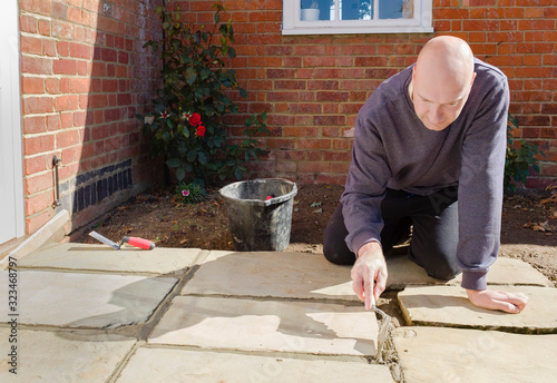 Builder laying York stone paving slabs, UK photo