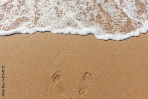 Footprints on the sand of the beach and white color of sea wave bubble