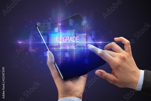 Businessman holding a foldable smartphone with UPGRADE inscription, new technology concept