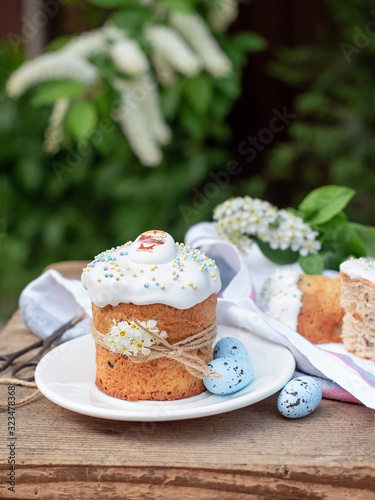 Easter composition with Easter cake, Kulich on the background of flowering branches of bird cherry in the garden. delicious easter dessert. vertical image