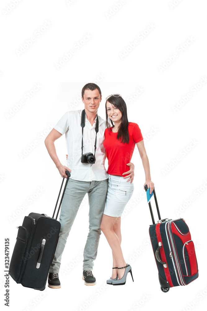 A couple in love, a young man and a woman with suitcases in their hands waiting for their flight, isolated on a white background. A man puts his arm around a woman's waist. A couple in love, a young man and a woman with suitcases in their hands waiting for their flight, isolated on a white background. A man puts his arm around a woman's waist.