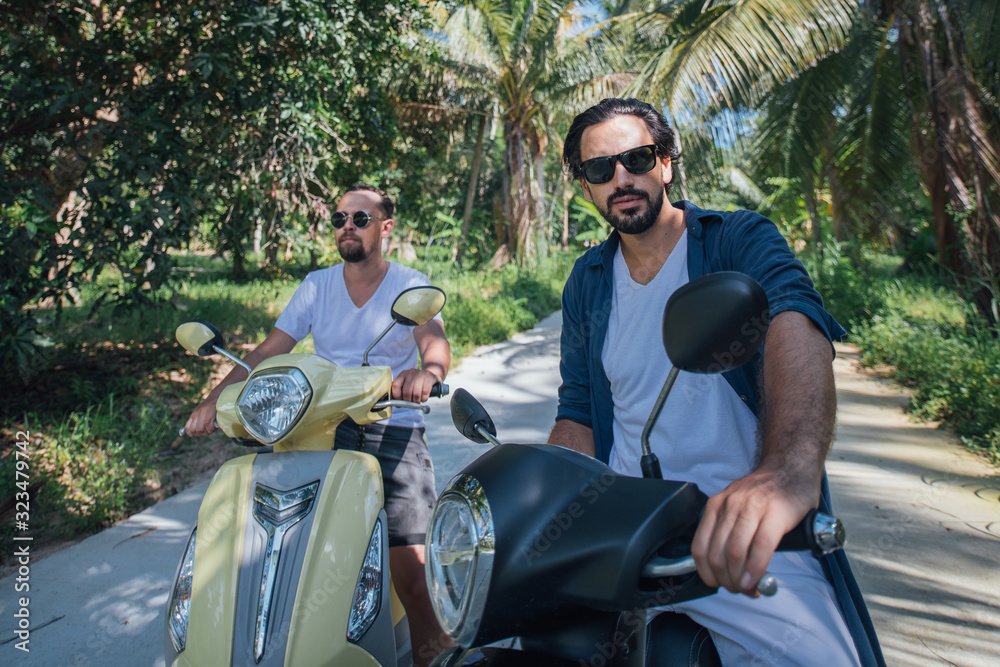 Naklejka premium Two men on motorcycles in palm trees on a tropical island