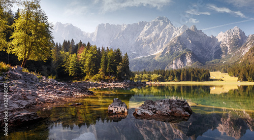 Awesome alpine highlands in sunny day. Scenic image of fairy-tale lake during sunset. Majestic Rocky Mountains on background. Wild area. Fusine lake. Italy, Julian Alps. Best travel locations.