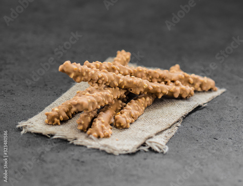 Straw cookies in caramel glaze with peanuts on a gray background in rustic style