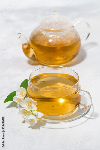 glass cup and teapot with jasmine green tea on a white background, vertical top view