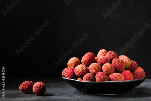 Fresh organic Lychee (Litchi fruit) in black plate on dark background. Close up. Copy space