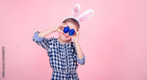 Portrait of a cute little girl with Easter eggs on a pink background.