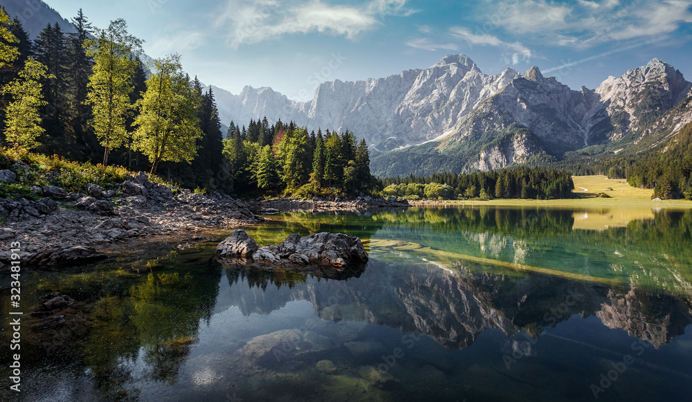 Awesome sunny landscape in the forest. Wonderful Summer scenery. Picturesque view of nature wild lake. colorful trees under sunlight. Incredible view on Fusine lakeside. Amazing natural Background