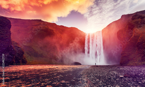Majestic nature of Iceland. Impressively View on Skogafoss Waterfall with colorful sky glowing sunligh, during sunrise. Skogafoss the most famous place of Iceland. creative artistic image