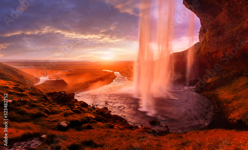 Seljalandsfoss the most famous Icelandic waterfall during sunset. A view of the colorful sky through the water that glows under the rays of the sun. impressively beautiful nature of Iceland. Postcard