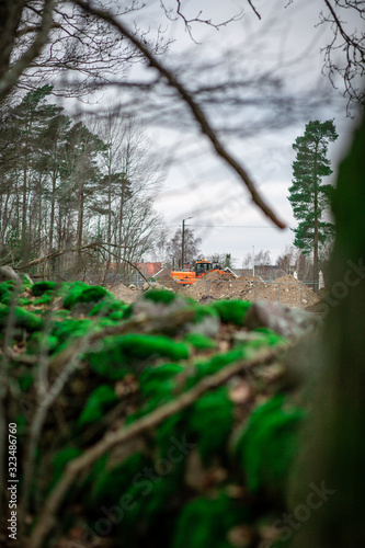 Excavator in the nature with green moss on stone wall in the foreground