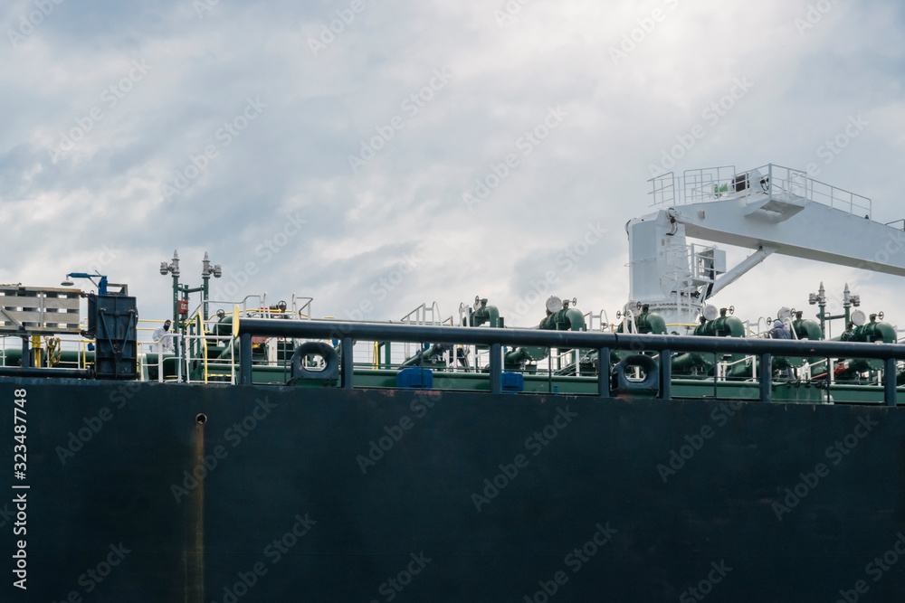 Abstract industrial or transport background illustrating shipping  and logistics featuring detail of large black and brown bulk ship board in sea port with mechanisms.