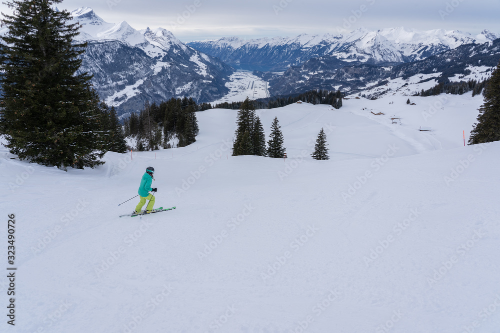 Girl hits the ski slope in Swiss mountains at cloudy day.