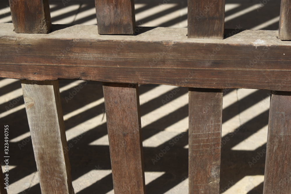 A fence of wood and a shadow on the floor A fence of wood and a shadow on the floor