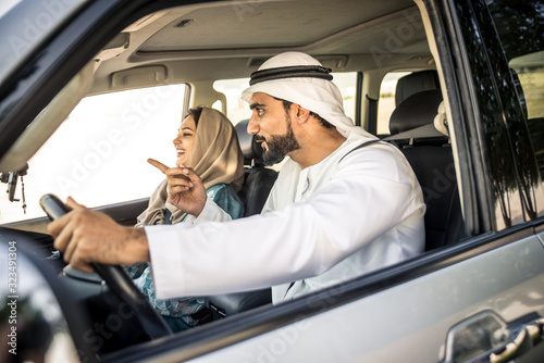 Happy couple driving the car in Dubai. Man and woman going out for shopping. Concept about relationship in the uae