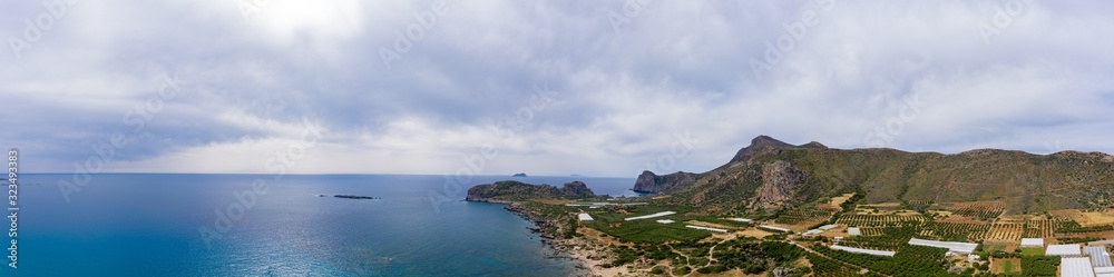Panoramic aerial view of Falasarna on Crete island, Greece with turquoise water and sandy beaches for rest. used for agriculture: greenhouses and gardens of olive trees.