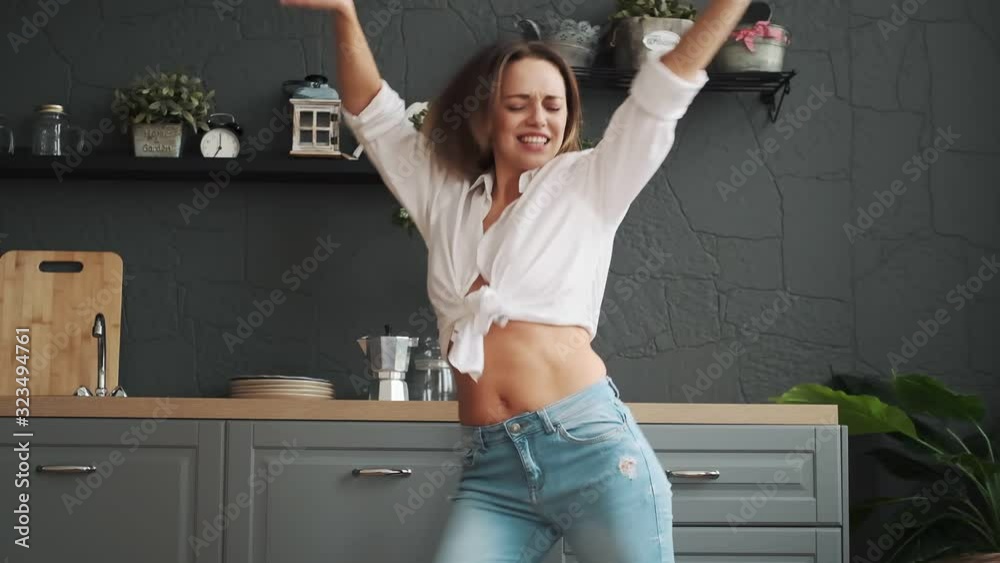happy woman dancing crazy in the kitchen in the early morning. girl is dancing happily and carefree at home.