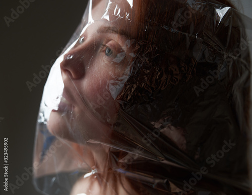 Portrait of a young girl with a plastic bag on her head. The concept of plastic pollution of nature. Excess plastic in a person's life       photo