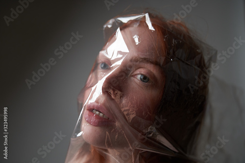 Portrait of a young girl with a plastic bag on her head. The concept of plastic pollution of nature. Excess plastic in a person's life       photo