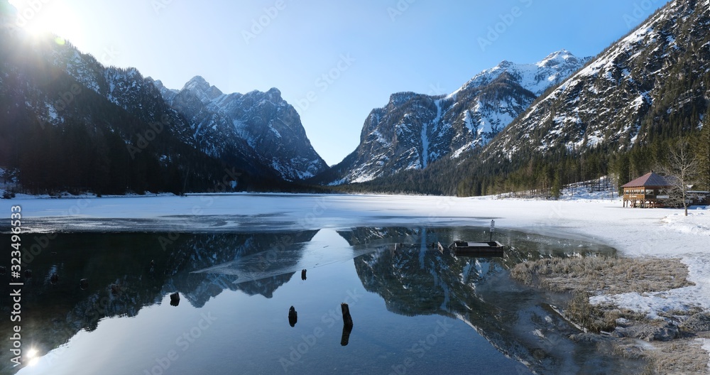 Fototapeta premium A beautiful magical view of the mountains reflected in the water in the morning sunlight. Lake Toblacher See (Dobbiaco) in South Tyrol, Dolomites, Italy