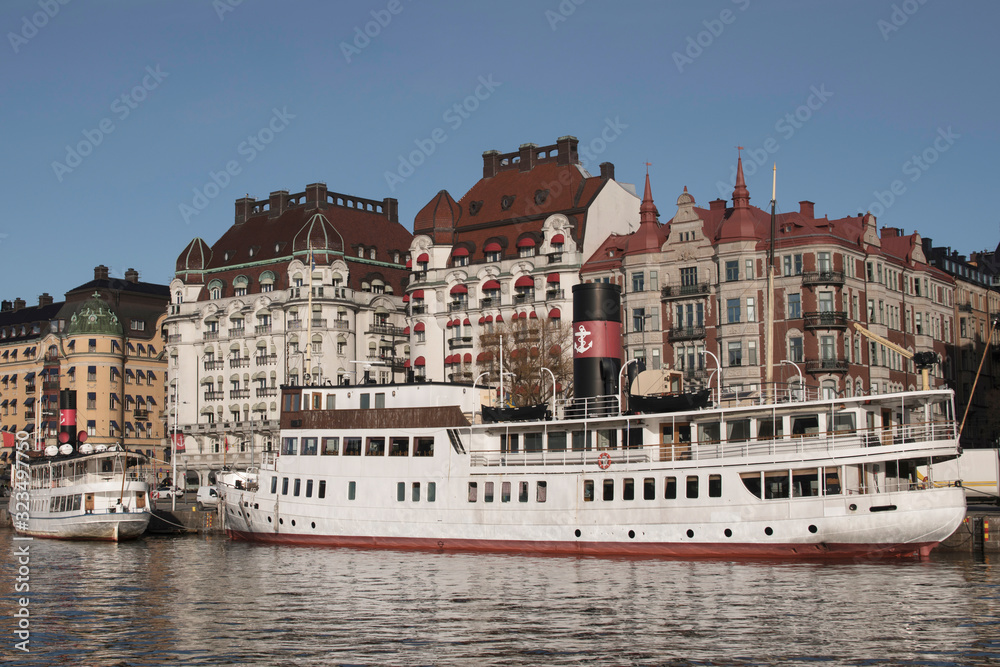 Naklejka premium Harbor view with boats and residential houses at the waterfront of the district Östermalm in Stockholm a sunny winter day