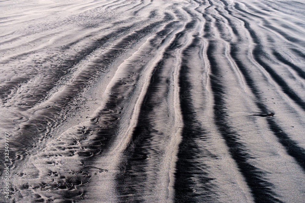 Vertical black lines in beach sand fade off into the distance Vertical black lines in beach sand fade off into the distance