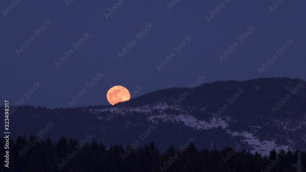 moonrise over wooded hills in winter