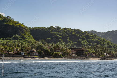Green rolling hills with houses on seashore in Thailand