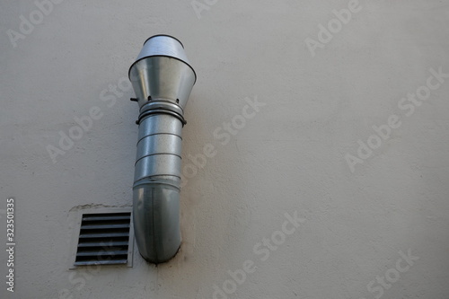  Extractor. Ventilation. Aluminum  pipe of an extractor hood on a white outer wall  
