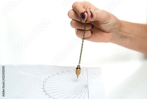 Arm of dowser with hand-held pendulum over the chart. Selective focus. photo