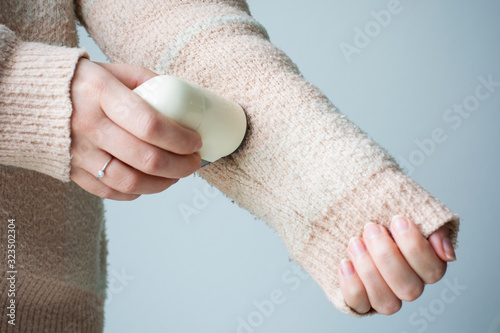 Pilled sweater. Woman wearing an old sweater with lint (pilling). Woman use handheld electric fabric shaver fuzz remover device machine for removing fuzz, lint and pills on clothes photo