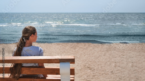 Girl with long hair looking towards the open sea