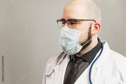 Male doctor in a white coat and a medical mask. Gray background.