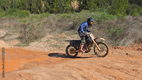 Zoom photo of mud track enduro motocross rider performing freestyle stunts in high speed