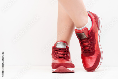 Red sport shoes on female legs close up background. Front view.
