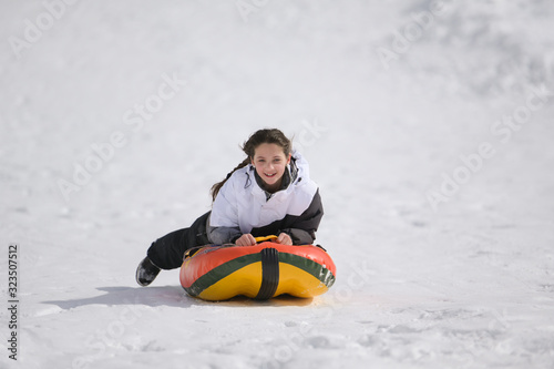 happy active sport healthy little girl with smile on her face during snow winter leisure games riding tubing on rubber tube with fast speed on travel holiday vacation