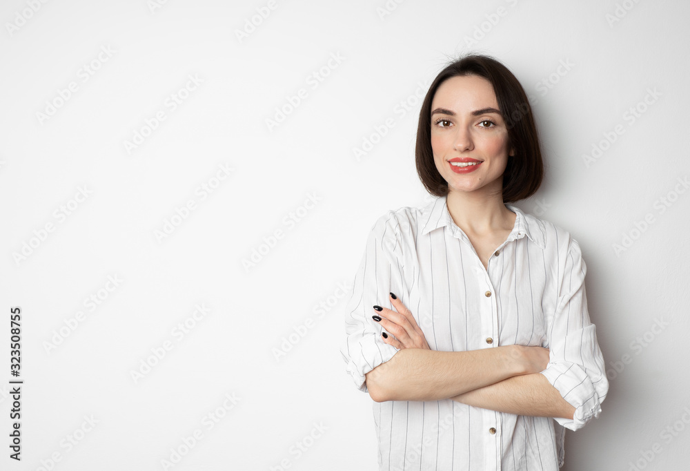 Beautiful looking at the camera with folded arms. Portrait of a cute girl in a black shirt on a white background. Beautiful looking at the camera with folded arms. Portrait of a cute girl in a black shirt on a white background.