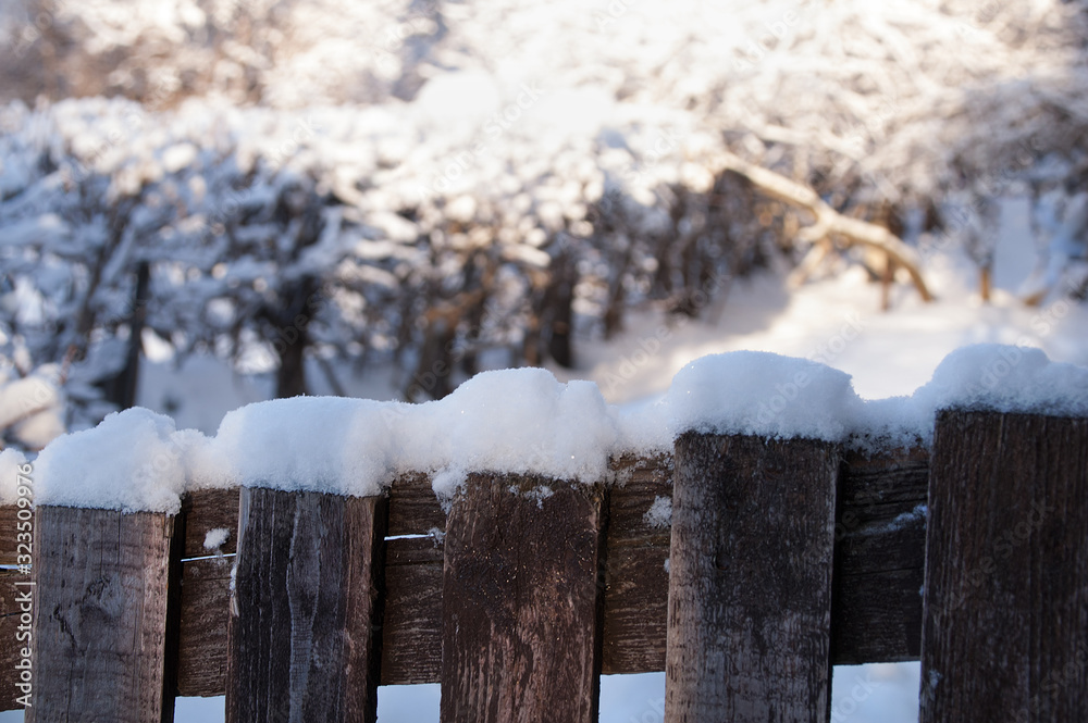 Snow on a wooden fence in the winter afternoon outdoors.