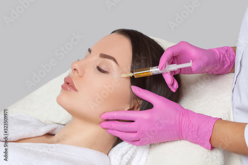 Cosmetologist does prp therapy anti wrinkle and aging skin on the face of a beautiful woman in a beauty salon. Cosmetology concept.